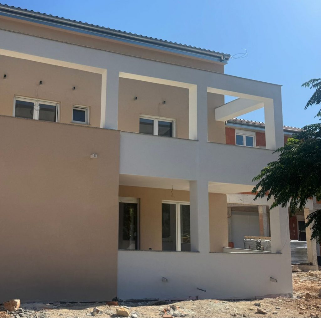 Azedara Apartments. Blick von der Straße auf das verputzte Gästehaus