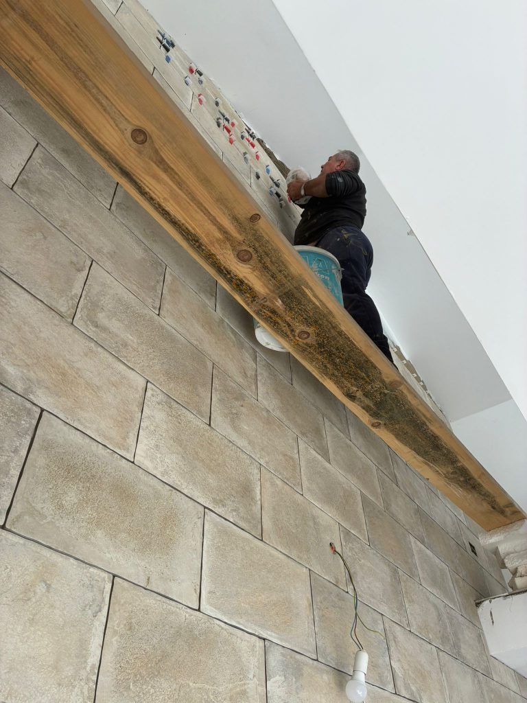 Baustellenbild. Fliesenleger bei der Arbeit. Giebelwand Apartment Lavanda.